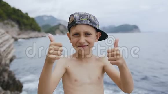 一个快乐迷人的男孩戴着帽子在海上欢呼成功的肖像可爱的孩子在海上欢呼视频的预览图