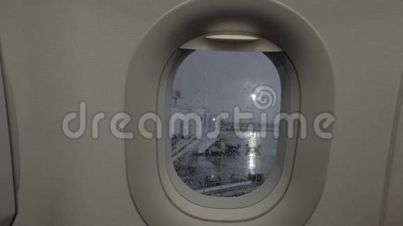 一个舷窗和一个下雨的机场庭院后面的特写视频的预览图