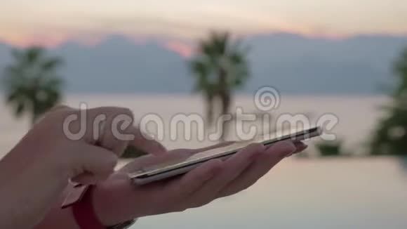 一个特写镜头女性双手在智能手机屏幕上敲击一条信息以抵御夏日的风景视频的预览图