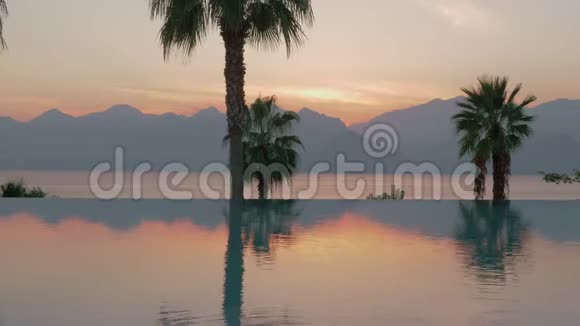 一个稳定的镜头一个光滑的游泳池边界和一个晚上的海洋景观的背景视频的预览图