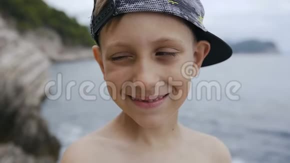 漂亮的小男孩蓝眼睛看着相机特写一个戴帽子的小男孩在镜头前眨眼睛视频的预览图