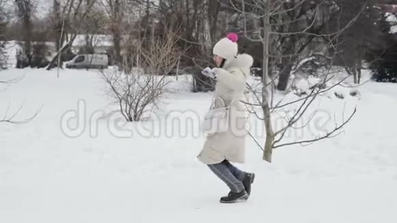 布鲁内特的头发年轻妇女粉红色的嘴唇米色羽绒大衣和帽子有趣的舞蹈雪中央公园降雪慢慢视频的预览图