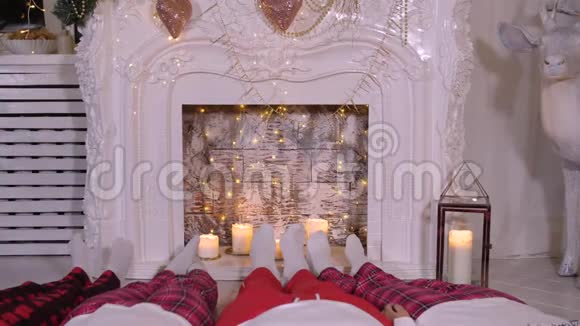 家庭在家放松脚穿圣诞袜子靠近壁炉寒假概念视频的预览图