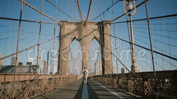 快乐的男人在电话中交谈在炎热的夏天4K离开镜头后沿纽约布鲁克林大桥的视线视频的预览图
