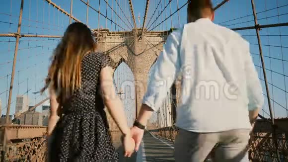 浪漫情侣漫步纽约布鲁克林大桥在美丽的夏日牵手亲吻后景低角度4K视频的预览图