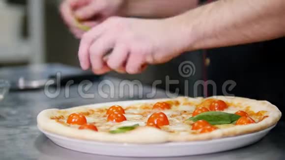 餐厅厨房一位厨师用绿色装饰披萨视频的预览图