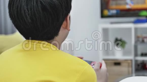 背面观看亚洲男孩在家玩电子游戏慢动作视频的预览图