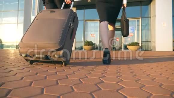 商务男女带着行李去机场年轻商人带着轮子的手提箱视频的预览图
