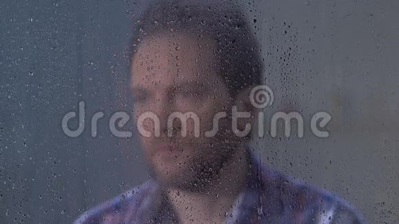 沮丧的中年男性望着雨窗思考孤独视频的预览图