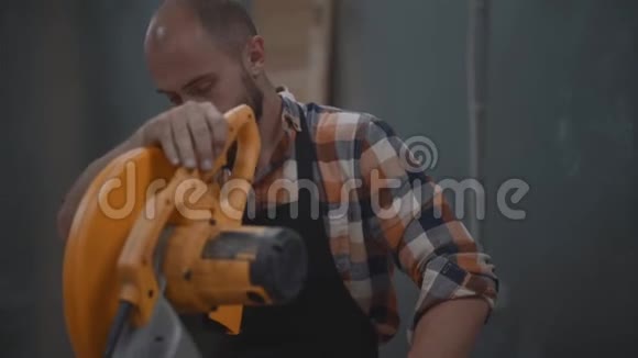 在工厂使用电动角磨床的长胡子机械火花四散金属加工塑料的加工过程视频的预览图