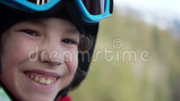 戴着头盔和护目镜的青少年男孩坐在滑雪电梯舱里孩子开心地笑了在山上度过有趣的假期视频的预览图