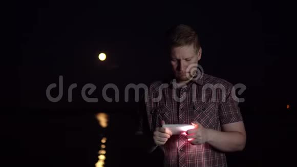 一个年轻人正在用智能手机相机拍摄一个红色的月亮视频的预览图