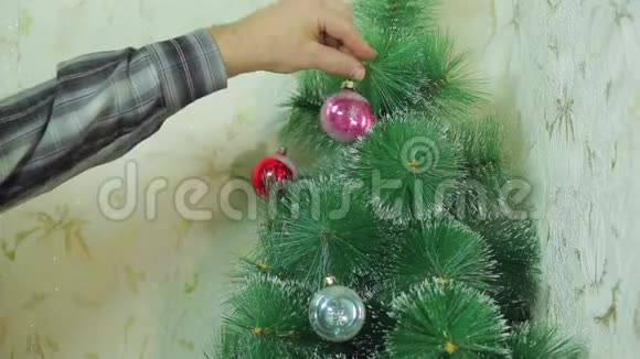 男人的手在圣诞树上挂着节日的球视频的预览图