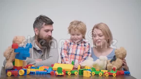 年轻的家庭玩游戏与建筑塑料块家庭游戏的概念父母和孩子的脸都红了视频的预览图