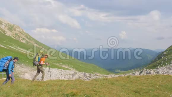 一群徒步旅行的人在青山和天空背景的山上旅行视频的预览图