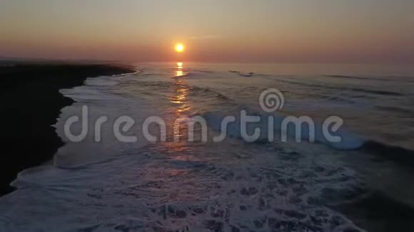 鸟瞰无人机的海浪在岸上坠毁的镜头在日落的高空飞翔视频的预览图
