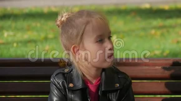 坐在公园长椅上吃三明治的小女孩视频的预览图