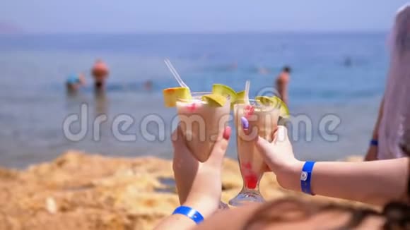 两个异国情调的鸡尾酒在埃及的海洋和海滩背景下的女孩手中视频的预览图