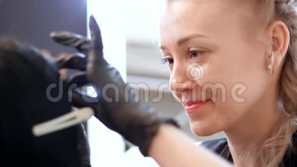 美容院一位大师的肖像一位美容师戴着黑色橡胶手套和一位客户一起工作非常喜欢她的工作视频的预览图