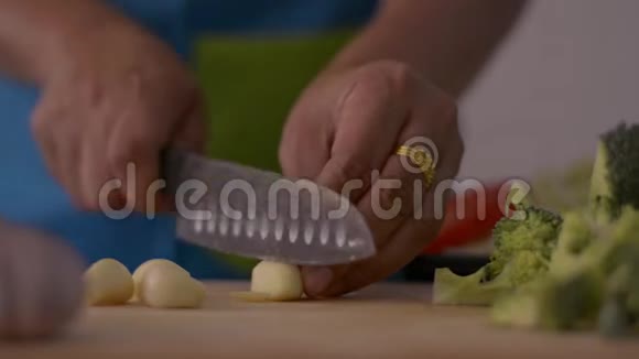 将女性手切大蒜的特写镜头放在木制砧板上供桌上健康食品食用视频的预览图