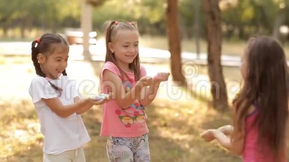 在阳光明媚的夏日孩子们花时间在草坪上玩五颜六色的沙子玩得很开心夏天幸福快乐视频的预览图