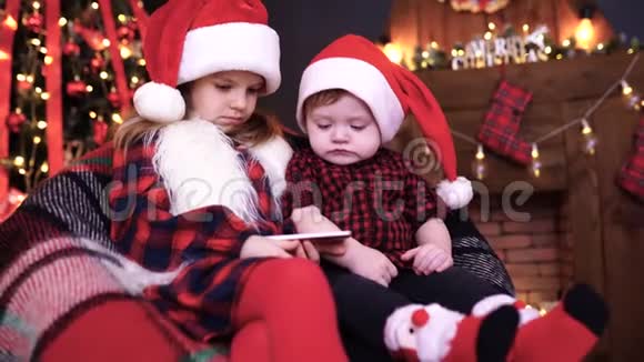 两个孩子在圣诞装饰品上玩智能手机视频的预览图