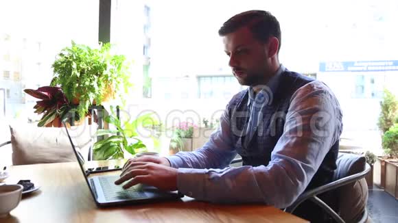 自由职业者商人在咖啡馆里用笔记本电脑和电话交谈视频的预览图