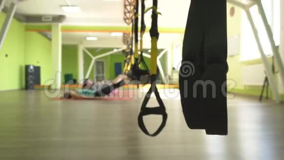 教练在健身房教一个人在练习面部推力时练习一个人在TRX的铰链上视频的预览图