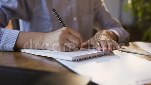 年轻女孩在现代办公室里用文件和笔记本电脑工作一个女人她的手写在白色空白笔记本上视频的预览图