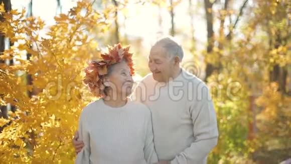 在一个美丽的秋天环境中一对老年夫妇在公园里拥抱和微笑老了视频的预览图