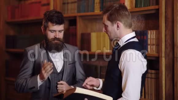 男性教授或教师在图书馆看书的肖像两位科学家在图书馆的讨论视频的预览图