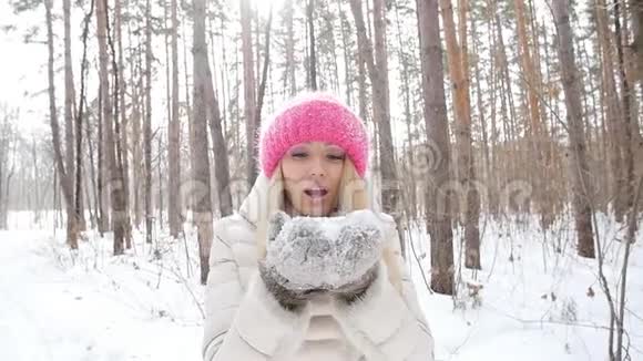 冬季娱乐理念一位年轻的女人在她手中吹着新鲜的雪视频的预览图