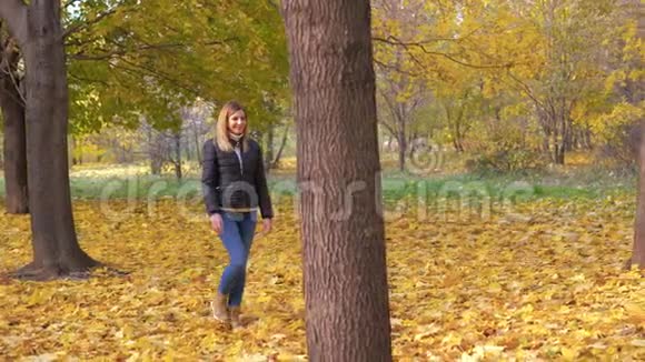 快乐微笑的白种人女人在秋天的公园里落叶漫步视频的预览图