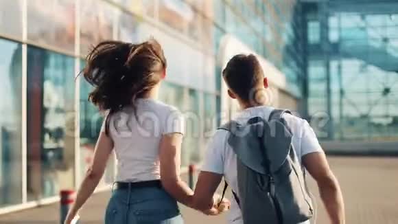 幸福的年轻夫妇手里拿着背包和护照跑到机场或火车站的概念视频的预览图