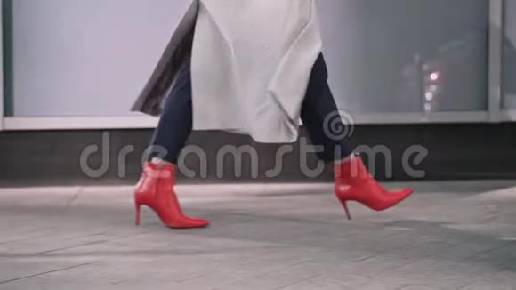 穿红色靴子的女人在秋街散步的腿视频的预览图