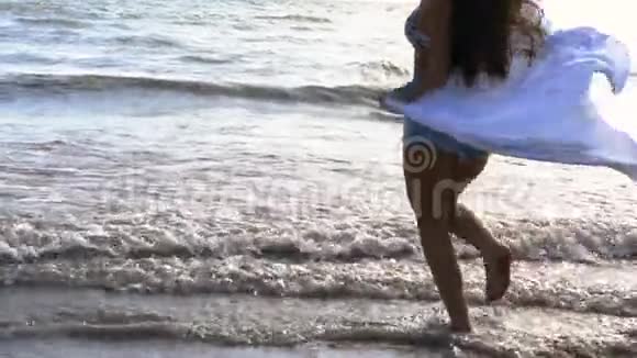 心情愉快的年轻女子向大海奔流的低角度视角视频的预览图