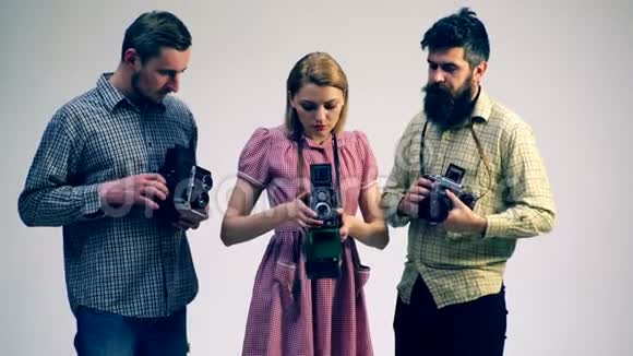 两个男人和一个女孩研究旧相机电影摄影机的概念视频的预览图