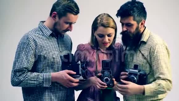 两个男人和一个女孩手里拿着旧相机研究照片打印的概念研究照片和视频的预览图