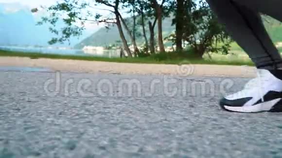 跟踪镜头女腿穿着运动鞋在湖边和山上跑步清晨在公园里训练女孩慢跑视频的预览图