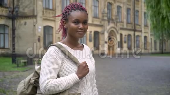 年轻的非洲女学生带着粉红色的恐惧症看着相机拿着背包站在公园附近视频的预览图