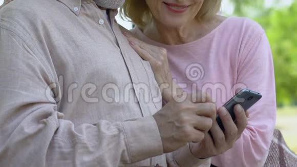 快乐的老夫妇看着智能手机和微笑通信技术视频的预览图