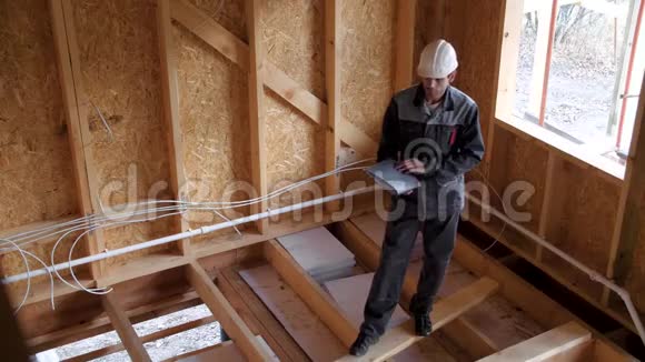 建筑师或建筑商检查半建木框架房屋的计划建筑工地上的建筑工人视频的预览图