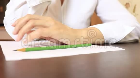 商务女性穿着白色衬衫坐在桌子旁拿着一张纸一支铅笔和敲击手指视频的预览图