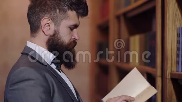 一个人站在书柜前读一本书成熟的人有着平静的脸喜欢读书图书馆概念视频的预览图