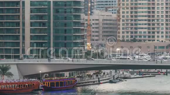 游艇和船只与游客停留在购物中心附近并通过桥下在迪拜码头地区的一天视频的预览图