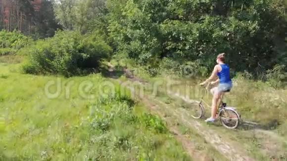 在森林附近的一片田野里女孩骑着一辆复古自行车视频的预览图