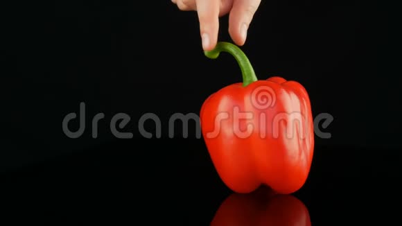 女性的手抓住胡椒的绿色尾巴和旋转美丽的成熟的红的甜的辣椒在镜子上旋转视频的预览图