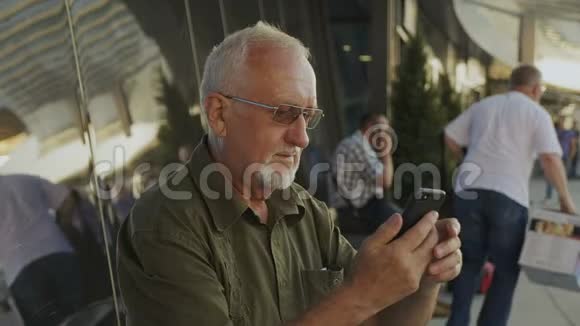 在户外使用智能手机的老人视频的预览图