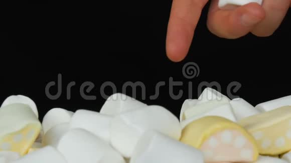 双手将五彩迷你棉花糖扔在镜子表面和黑色背景上糖尿病问题视频的预览图
