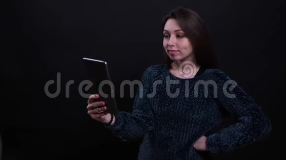 成年白种人深色头发的女性在平板电脑上播放一段视频背景是孤立的视频的预览图
